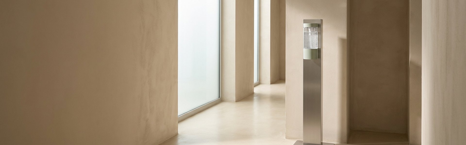 Distributeur gel hydroalcoolique sur pied dans un hall d'entrée moderne, design épuré, éclairage doux